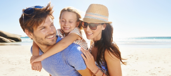 Mother and father laughing with their young son on the beach