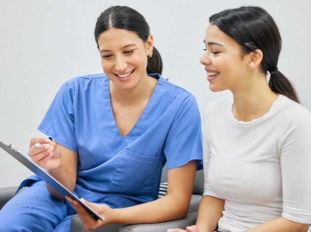 Dental assistant showing patient forms on clipboard