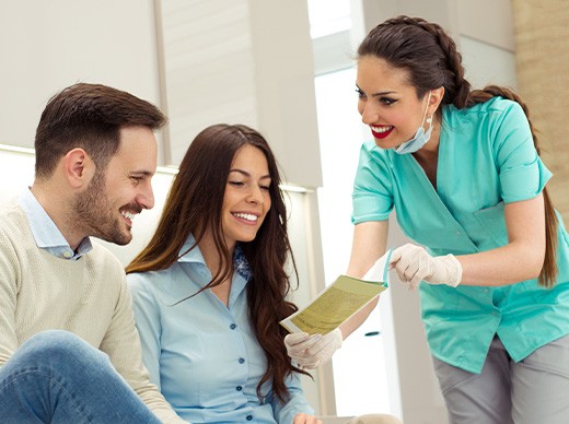 Dental assistant showing smiling couple form
