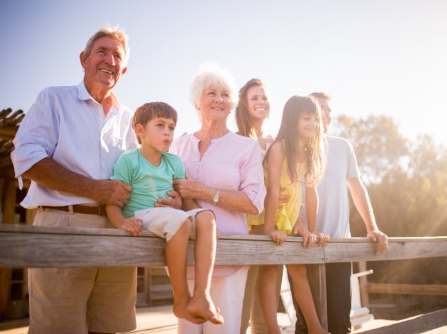 Three generations of smiling family standing on a bridge