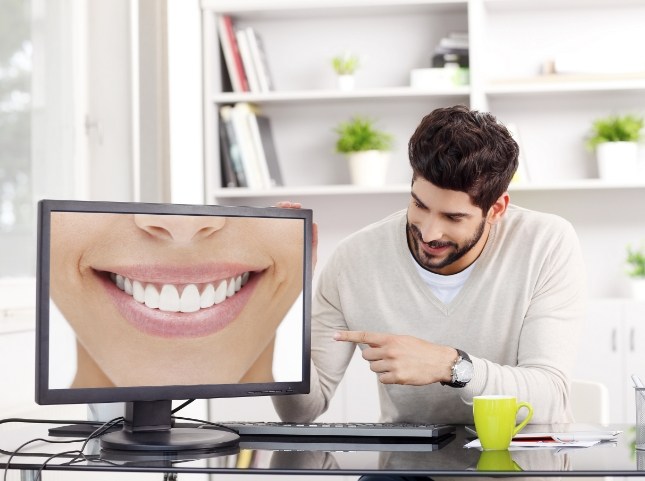 Man pointing to computer screen showing smile with flawless teeth