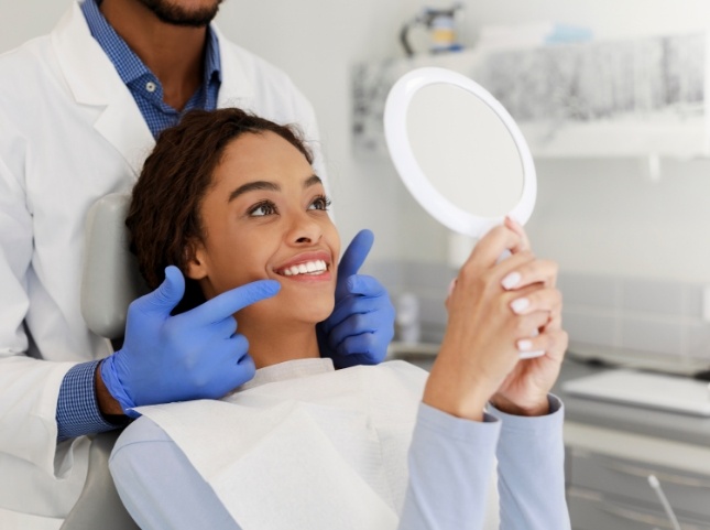 Woman in dental chair admiring her smile in mirror
