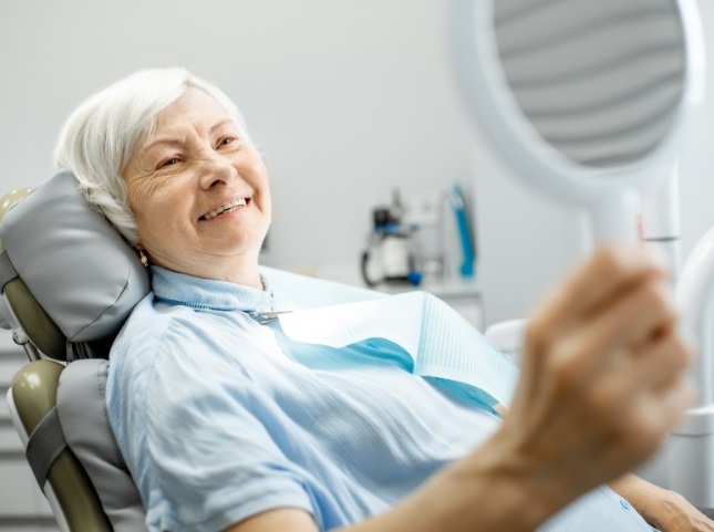 Senior dental patient admiring her smile in a mirror