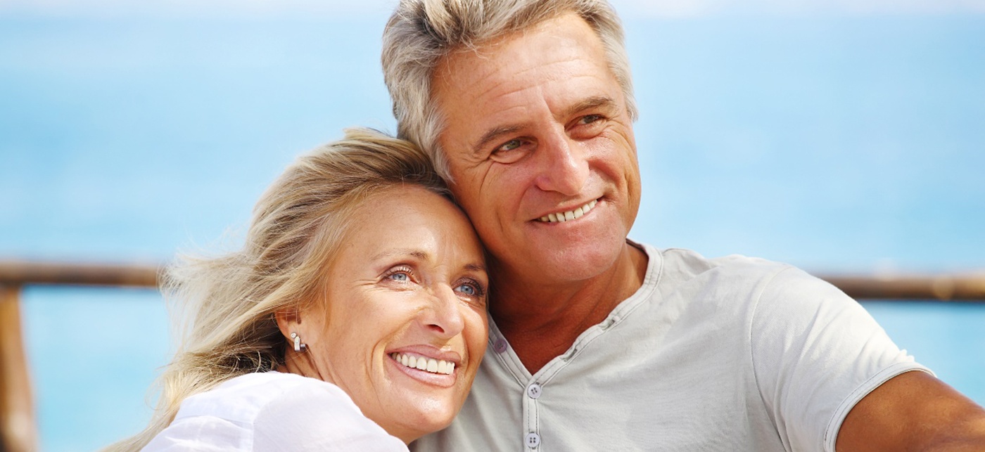 A smiling older couple looking into the distance while outdoors