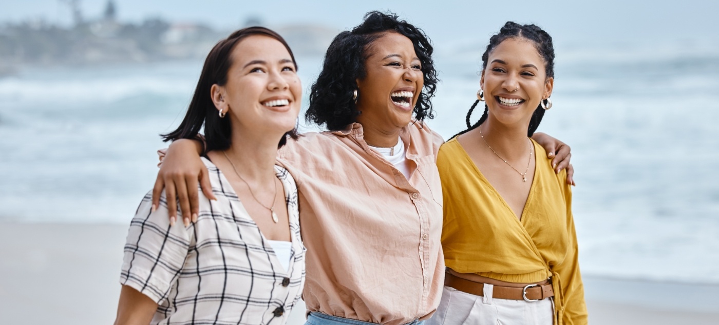 Three women laughing together on beach