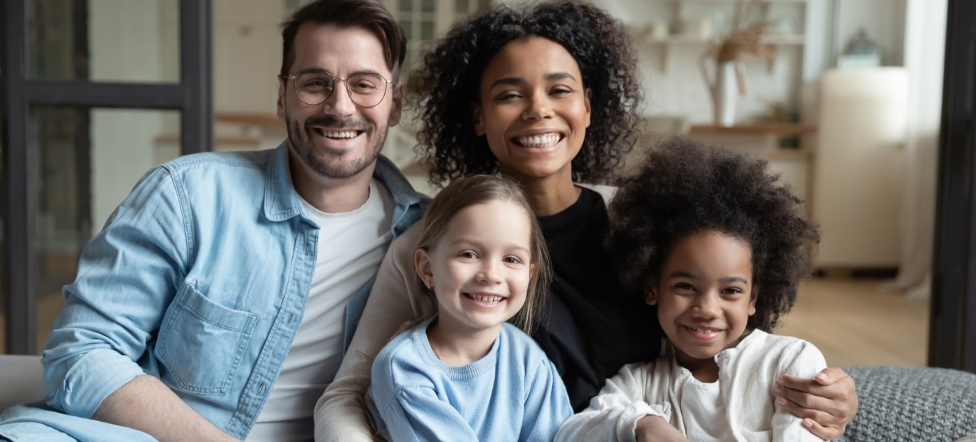 Family of four smiling on couch