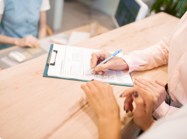 Dental team member showing a patient where to sign on a clipboard