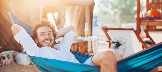 Man relaxing in hammock with beach in background