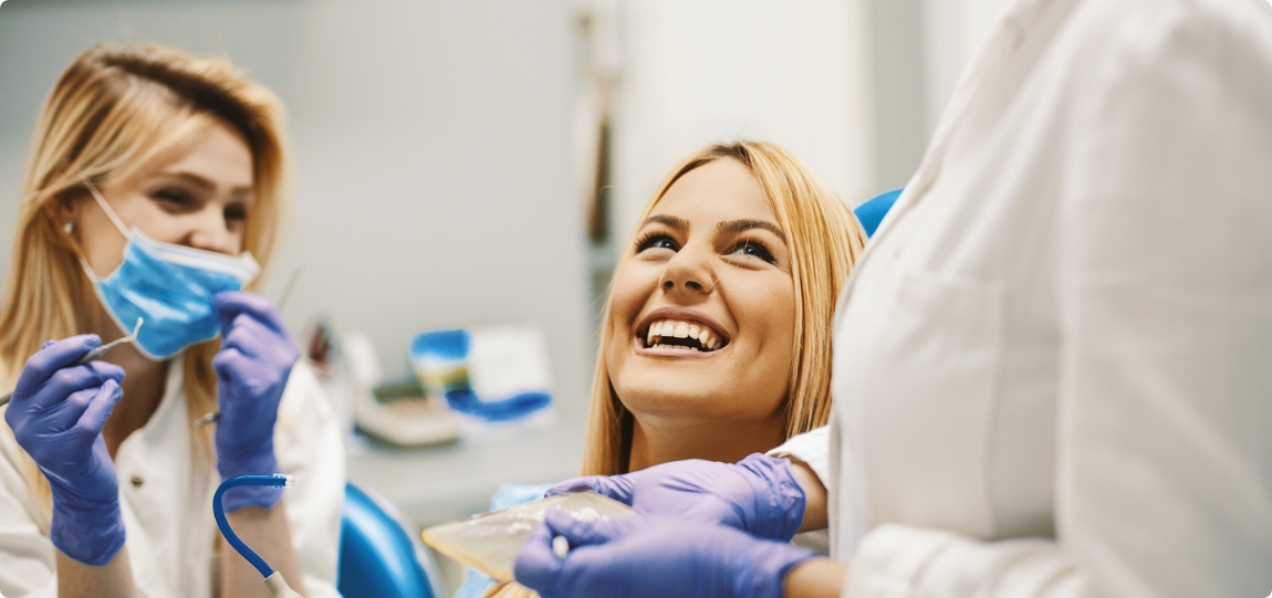 Woman in dental chair smiling up at her dentist