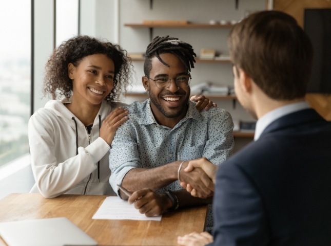 Man sitting at table shaking hands with man across from him