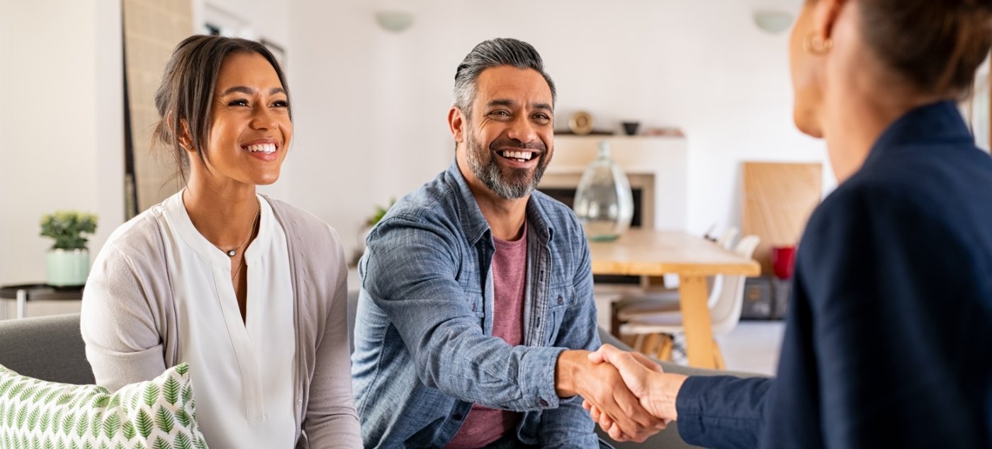 Man smiling and shaking hands with person sitting across from him