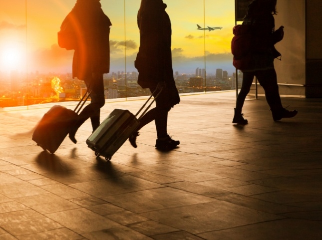 Three people carrying wheeled suitcases in airport