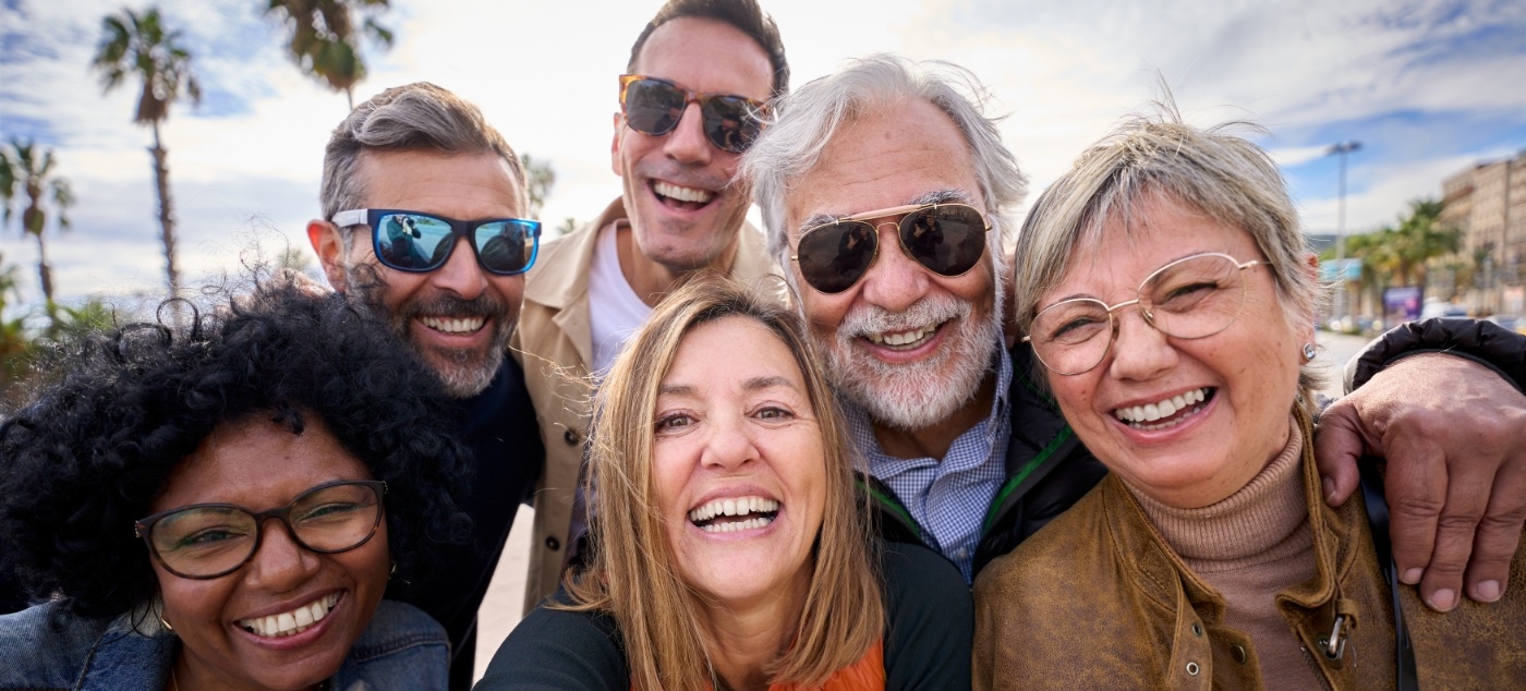 Group of older adults smiling after replacing missing teeth in Newark