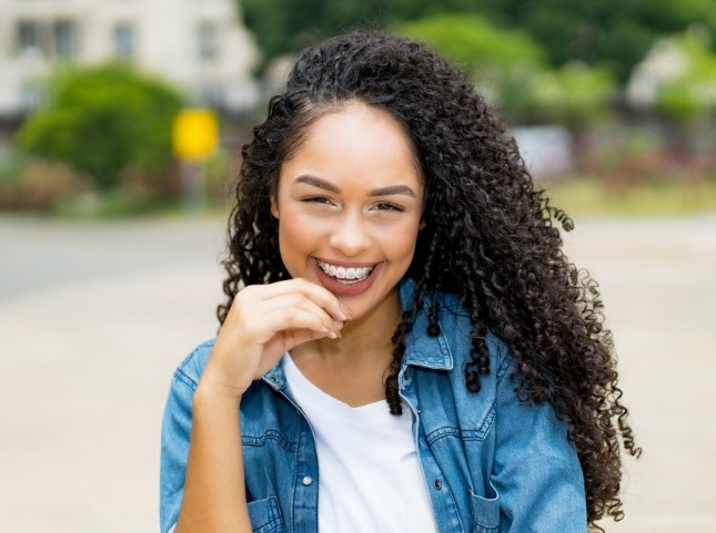 Young woman in denim jacket smiling with braces