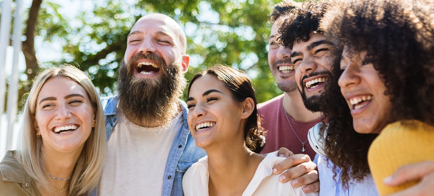 Group of young adults laughing together outdoors after dental services in Newark