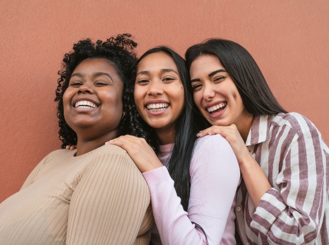 Three women laughing and standing in a row