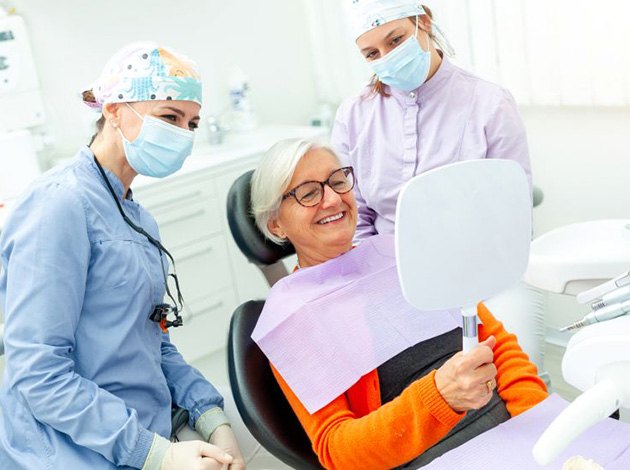 Happy senior patient admiring her smile in mirror