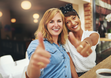 Two smiling women giving thumbs up