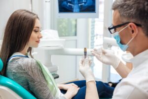 Dentist showing a dental implant to a young woman patient. 