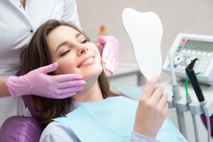 Young woman patient smiling in mirror at dentist's office.