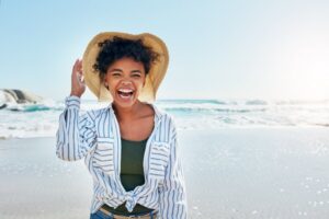 Woman laughing with white teeth at beach during summer